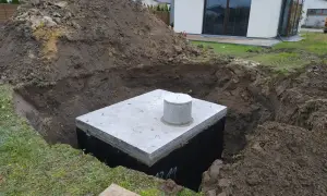 Zbiornik na deszczówkę czeka na zakopanie. Wykop jest głęboki, a ziemia usypana obok.