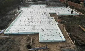 Fundament punktowy z rur szalunkowych, przygotowany do wylania betonu. Na placu budowy widać zbrojenie i izolację.