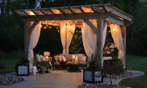 Urocza pergola z oświetleniem i zasłonami, idealna na letnie wieczory. Inspiracja, jak zrobić pergole, by stworzyć przytulne miejsce.