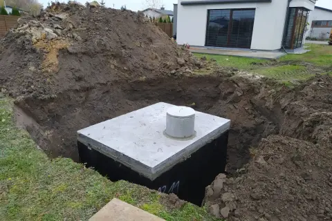 Zbiornik na deszczówkę czeka na zakopanie. Wykop jest głęboki, a ziemia usypana obok.