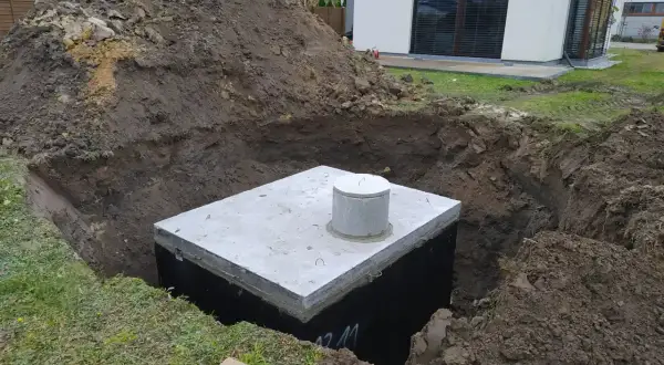 Zbiornik na deszczówkę czeka na zakopanie. Wykop jest głęboki, a ziemia usypana obok.