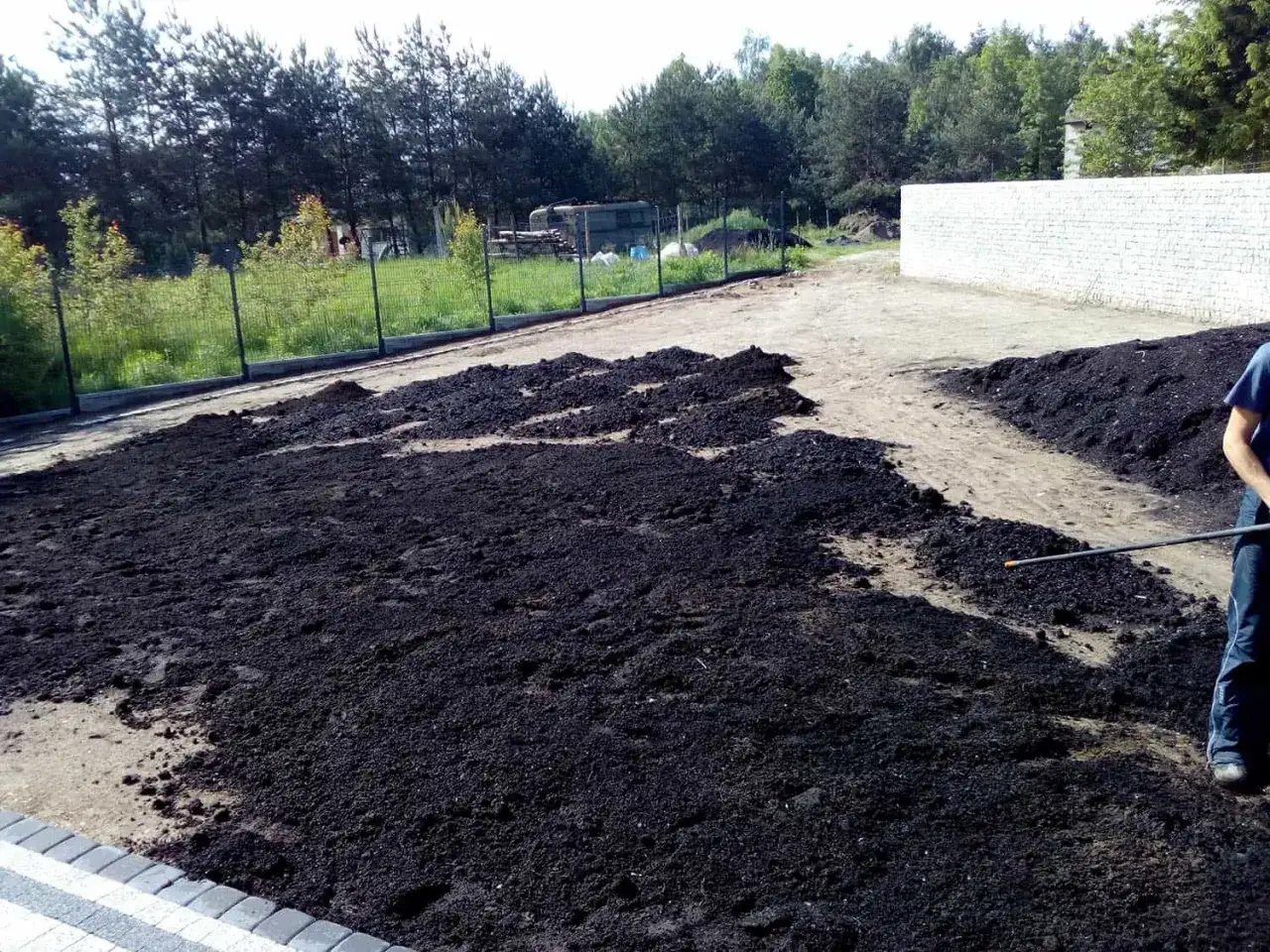Przygotowany teren pod zasiew trawy. Ciemna ziemia czeka na nasiona, idealny czas kiedy siać trawę.