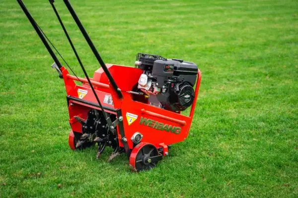 Czerwony aerator Weidemann z silnikiem Briggs & Stratton gotowy do pracy. Urządzenie zapewnia doskonałą wertykulację trawy, napowietrzając ją i usuwając filc.