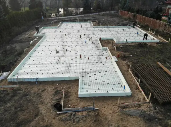 Fundament punktowy z rur szalunkowych, przygotowany do wylania betonu. Na placu budowy widać zbrojenie i izolację.